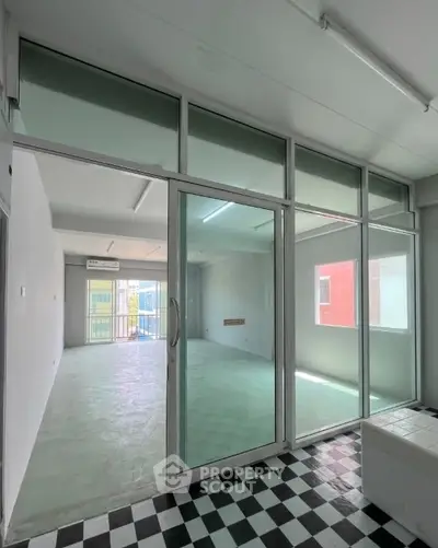 Spacious modern interior with large glass doors and checkered flooring, ideal for versatile living or office space.