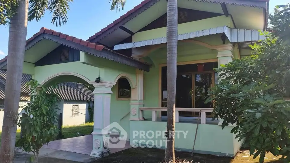 Charming green house with unique architectural design and lush surroundings.