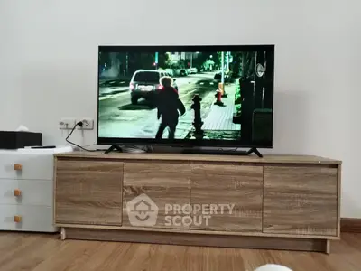 Modern living room with sleek wooden TV stand and flat-screen television, showcasing a cozy and stylish interior.