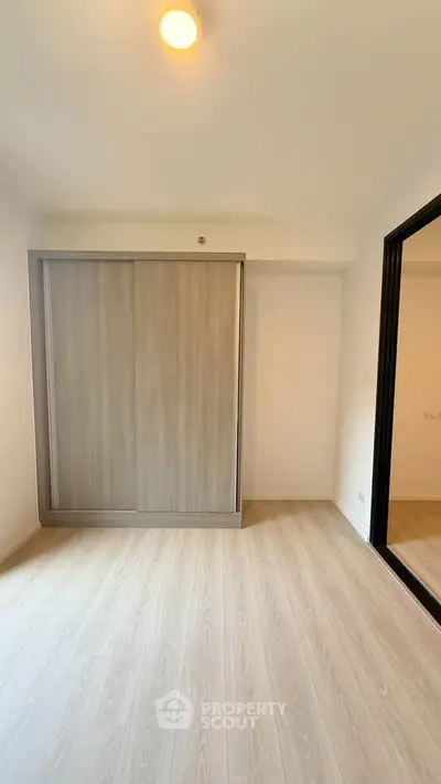 Spacious bedroom with sleek wooden flooring and modern sliding wardrobe