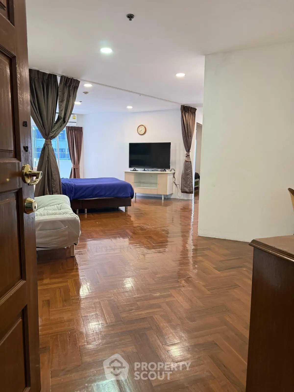 Spacious living area with polished wooden floors and modern furnishings in a stylish apartment.