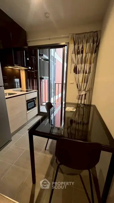 Modern kitchen with sleek black table and stylish curtains, featuring open layout and balcony access.