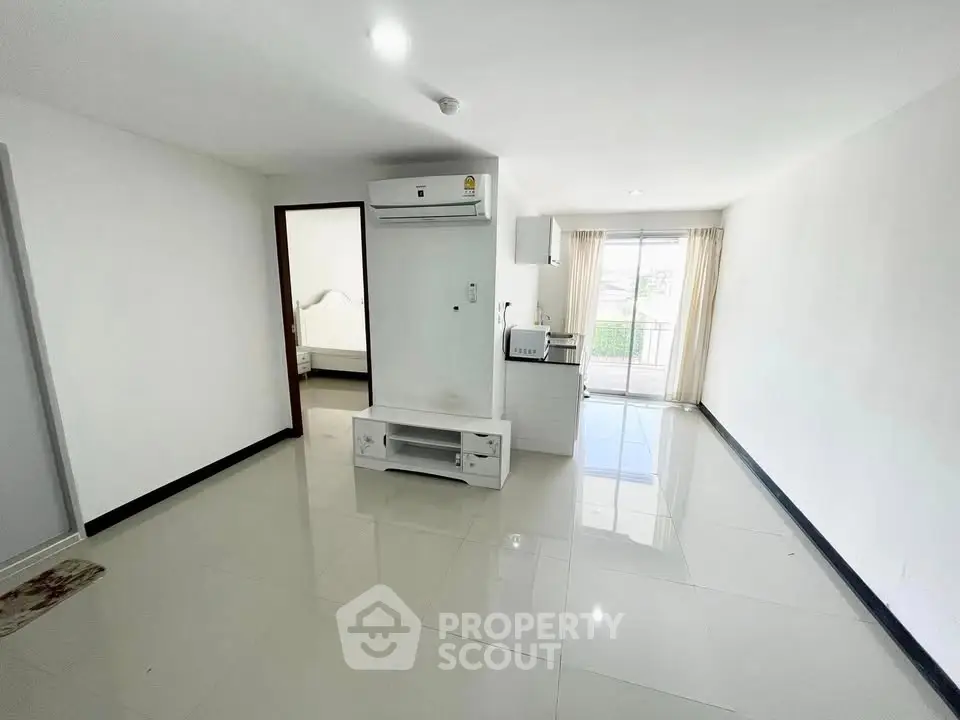 Spacious open-plan living area with modern kitchen and balcony access, perfect for urban living.