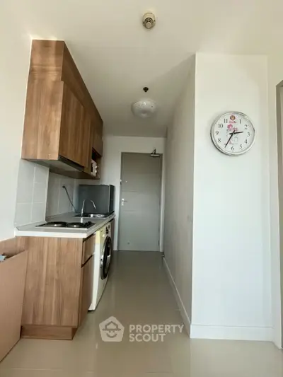 Compact kitchen with wooden cabinets and washing machine in modern apartment.