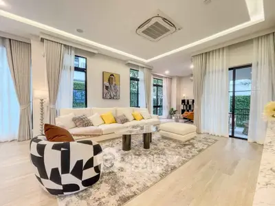 Luxurious modern living room with elegant decor and large windows offering natural light.