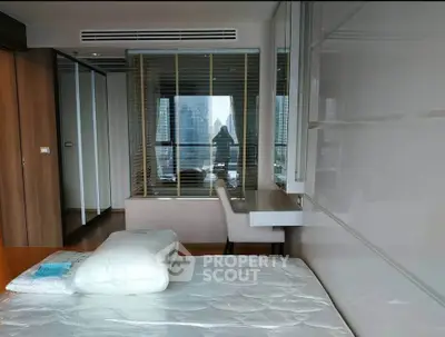 Modern bedroom with city view, featuring sleek furniture and large window for natural light.