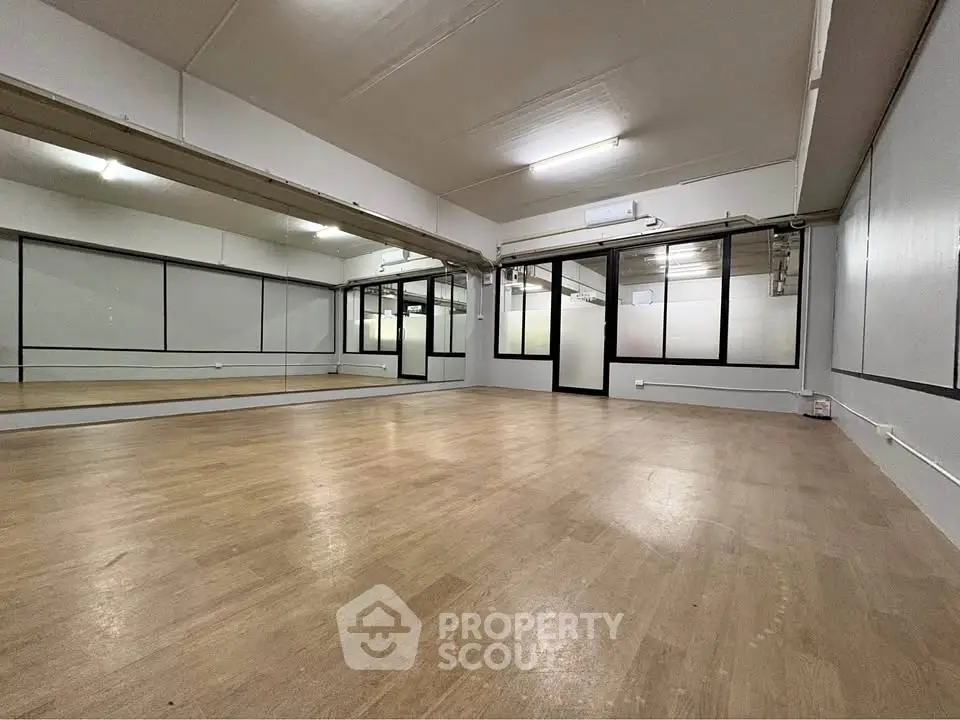Spacious studio with mirrored walls and wooden flooring, ideal for dance or fitness activities.