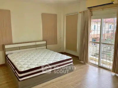 Spacious bedroom with large window and balcony access, featuring a modern bed and air conditioning.