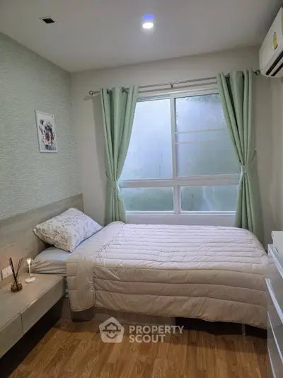 Cozy bedroom with single bed, soft lighting, and large window with green curtains.