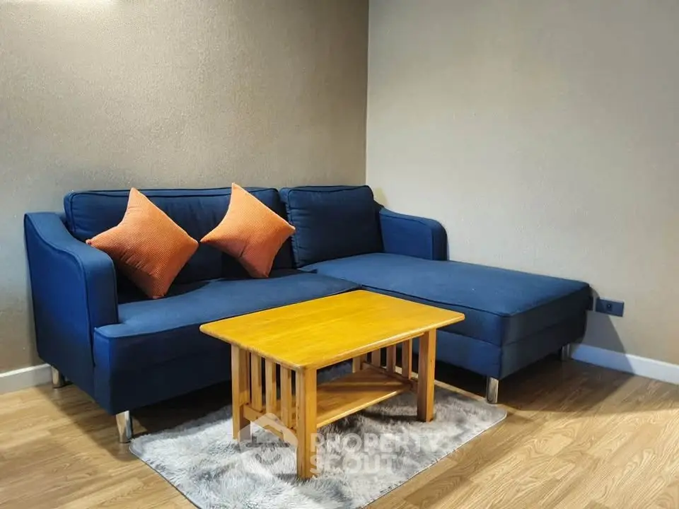 Cozy living room with blue sectional sofa and wooden coffee table on a plush rug.