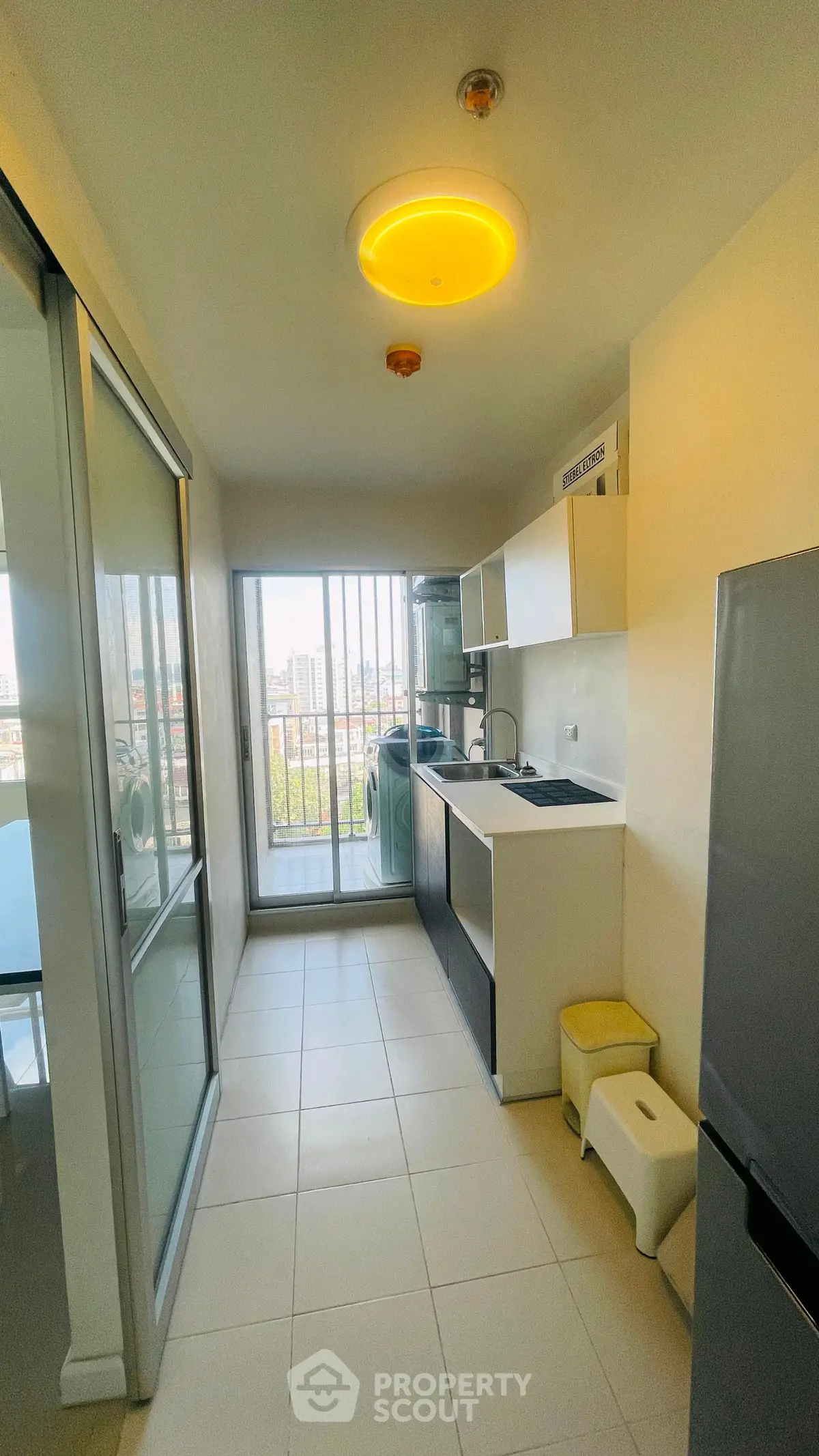 Modern kitchen with balcony view, featuring sleek appliances and ample natural light.