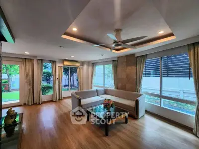 Spacious living room with modern design and large windows offering garden views.