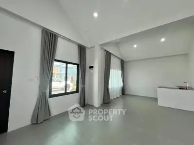 Spacious modern living room with large windows and elegant curtains in a minimalist home.
