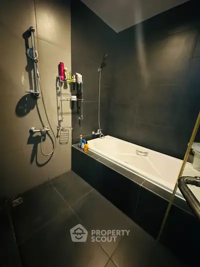 Modern bathroom with sleek dark tiles and a stylish bathtub.