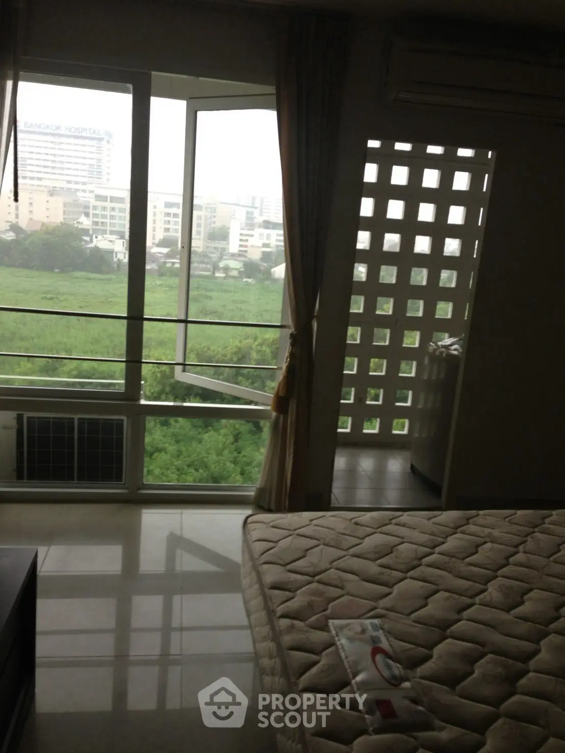Spacious bedroom with large window offering lush green views and ample natural light.