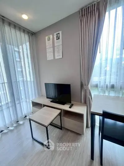 Modern living room with TV, stylish furniture, and large windows for natural light.