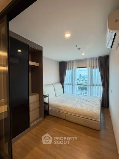 Modern bedroom with city view, featuring a comfortable bed and sleek wardrobe in a high-rise apartment.