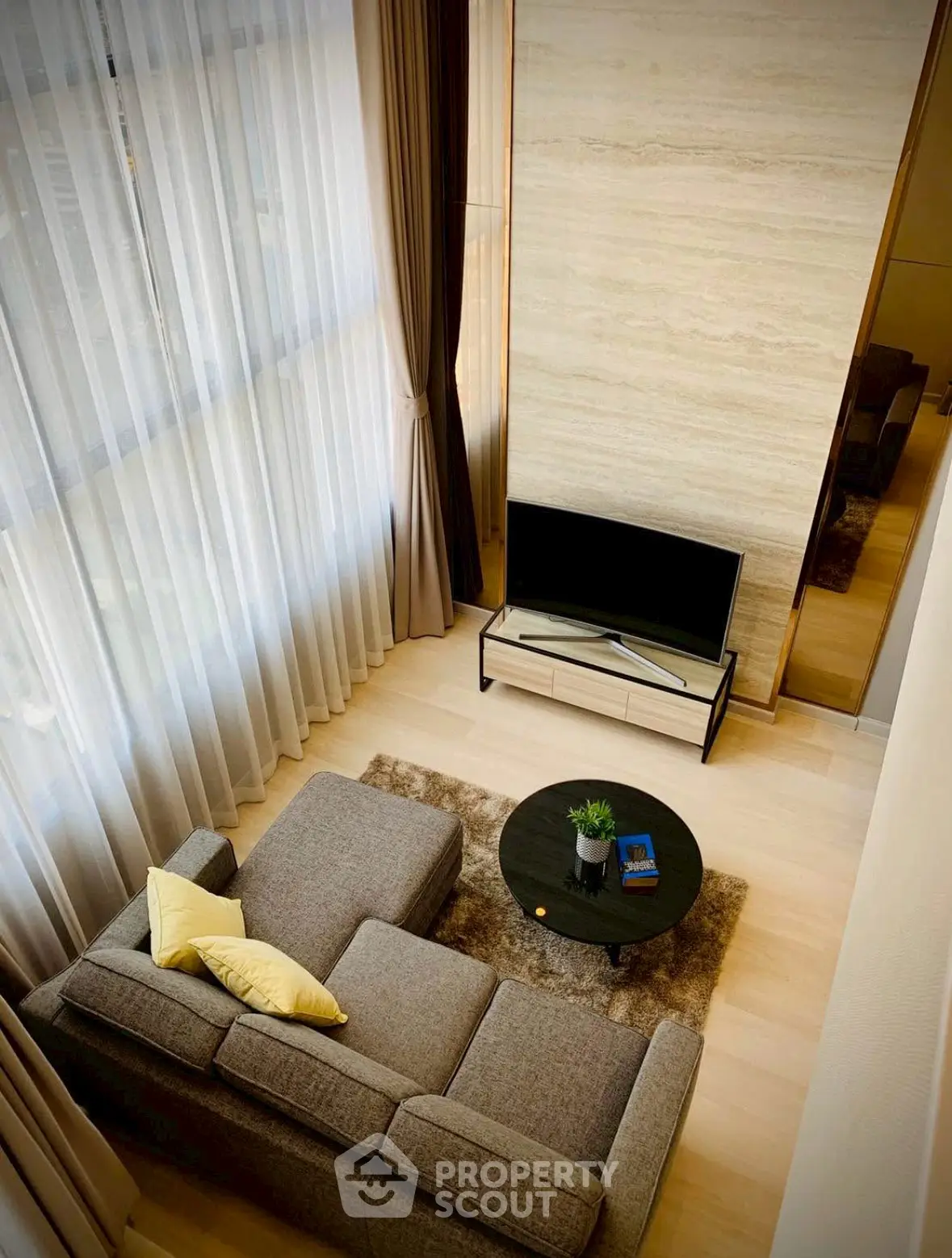 Modern living room with stylish sofa and TV, featuring floor-to-ceiling windows and elegant decor.