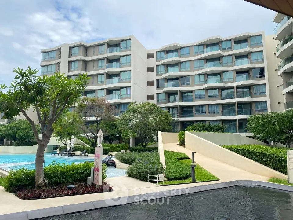 Modern residential building with pool and lush greenery, offering a luxurious lifestyle.