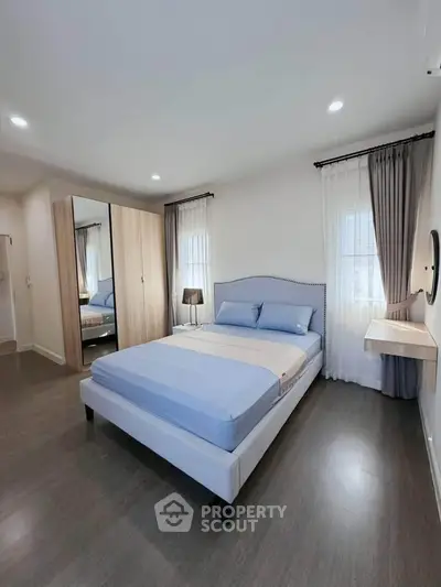 Spacious bedroom with modern decor and ample natural light, featuring a stylish bed and sleek wardrobe.