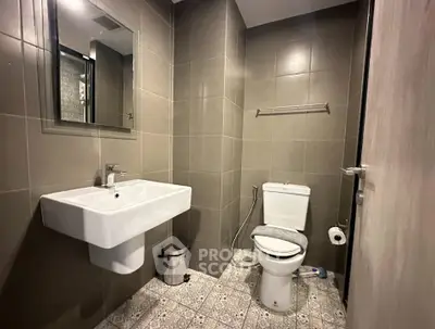 Modern bathroom with sleek fixtures and neutral tiles, featuring a stylish sink and toilet.