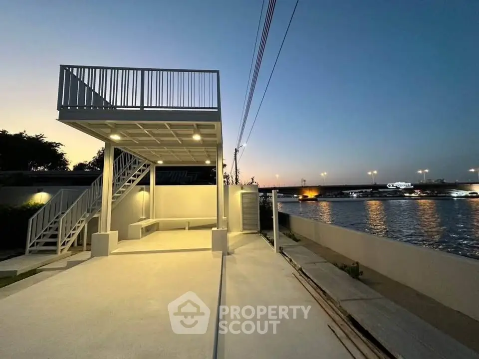 Modern waterfront property with elevated deck and stunning river views at dusk.