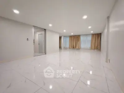 Spacious modern living room with marble flooring and large windows with curtains.