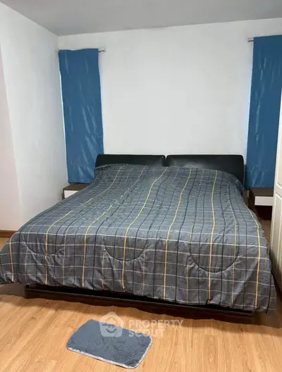 Cozy bedroom with stylish bedding and wooden flooring, perfect for relaxation.