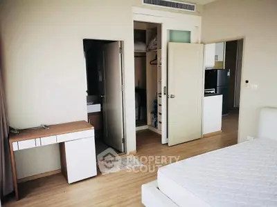 Spacious bedroom with modern design, featuring a walk-in closet and sleek wooden flooring.