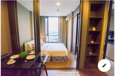 Modern bedroom with city view, featuring elegant decor and cozy dining area, perfect for urban living.