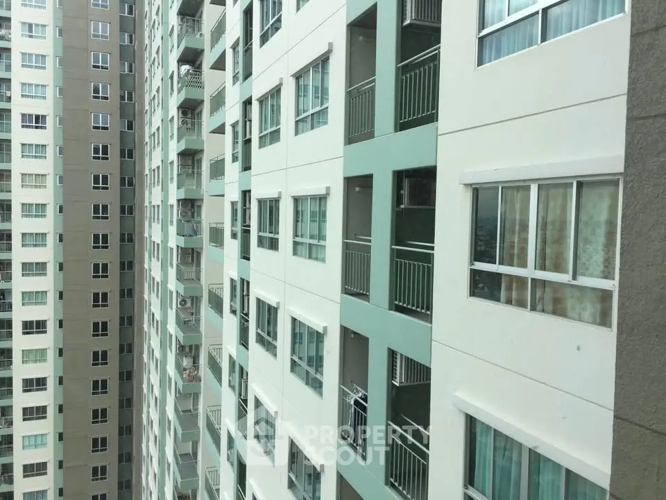 High-rise apartment building exterior with multiple balconies and windows.