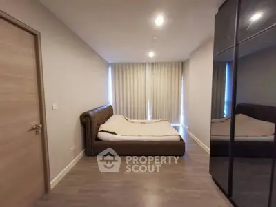 Modern bedroom with sleek design, featuring a cozy bed and mirrored wardrobe, perfect for urban living.