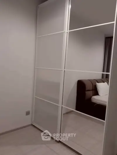 Modern bedroom with sleek mirrored wardrobe and cozy bed setup.