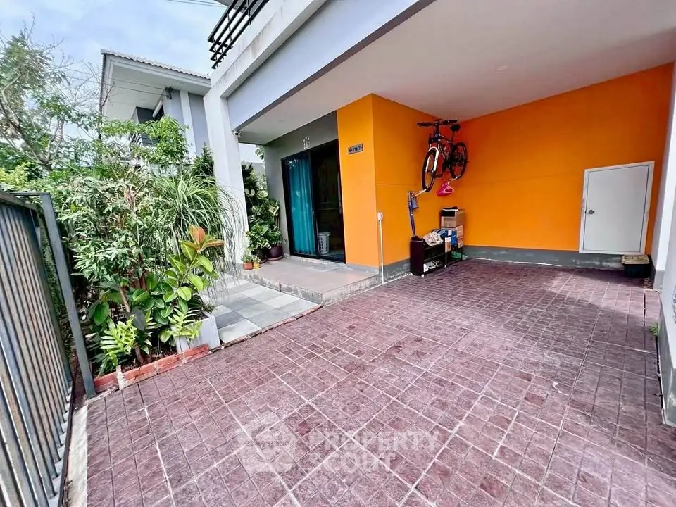 Charming modern home with vibrant orange exterior and spacious driveway, perfect for urban living.