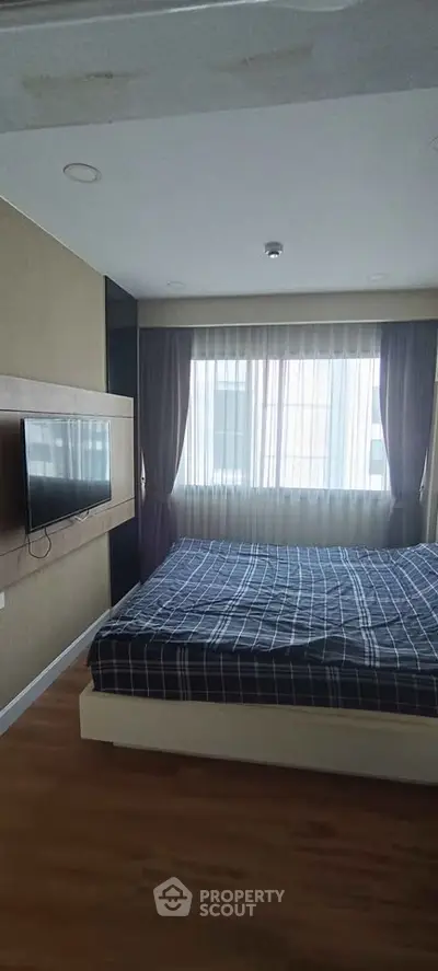Cozy bedroom with large window and modern decor, perfect for relaxation and comfort.