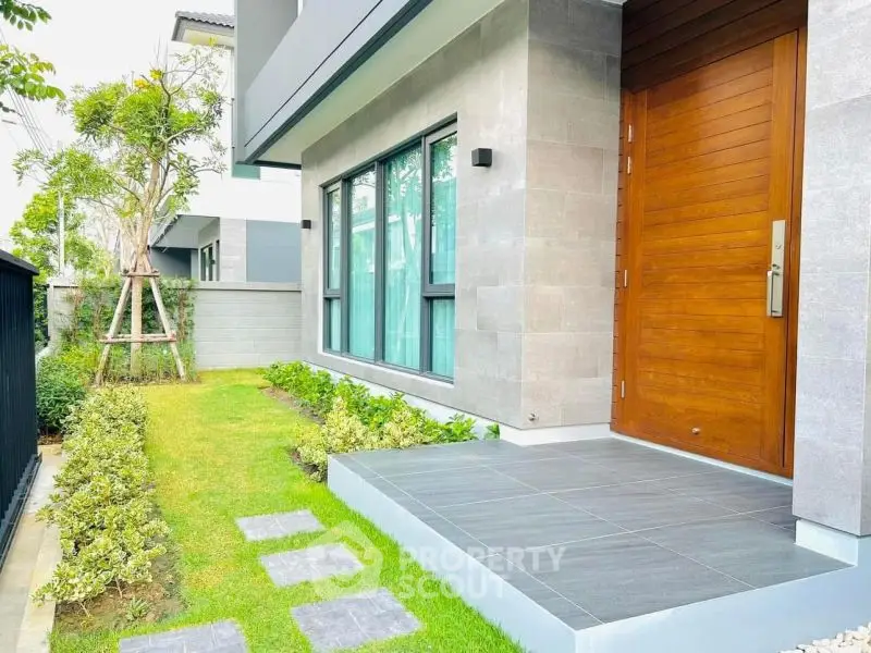 Modern home entrance with sleek wooden door and landscaped garden