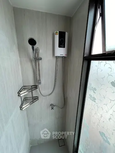Modern bathroom shower area with water heater and frosted window