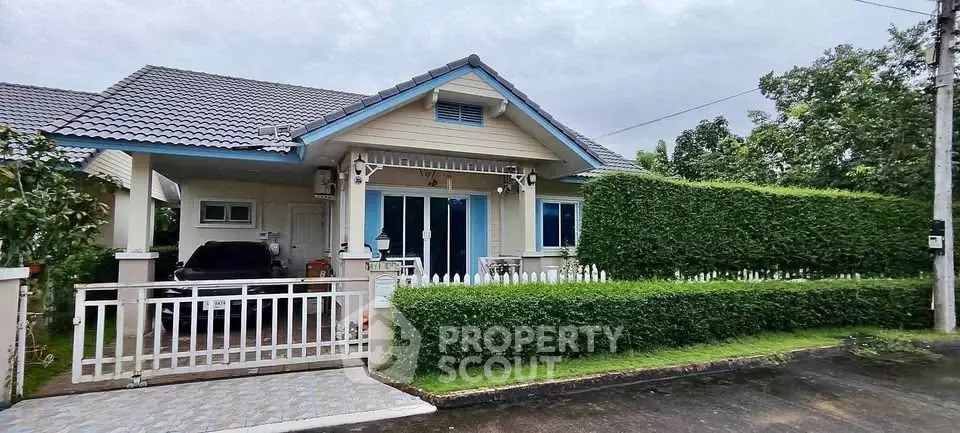 Charming single-story house with manicured hedge and gated driveway in a serene neighborhood.