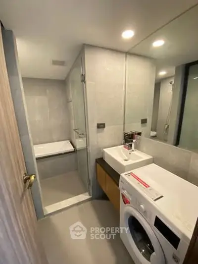 Modern bathroom with washing machine and glass shower enclosure