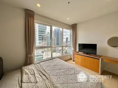 Modern bedroom with city view, featuring large windows, TV, and stylish furniture.