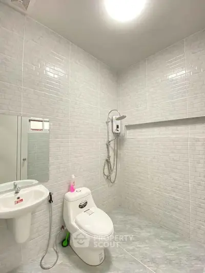 Modern bathroom with sleek white tiles and contemporary fixtures.