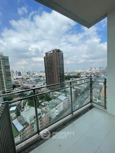 Stunning cityscape view from a high-rise balcony with modern railing and tiled flooring.