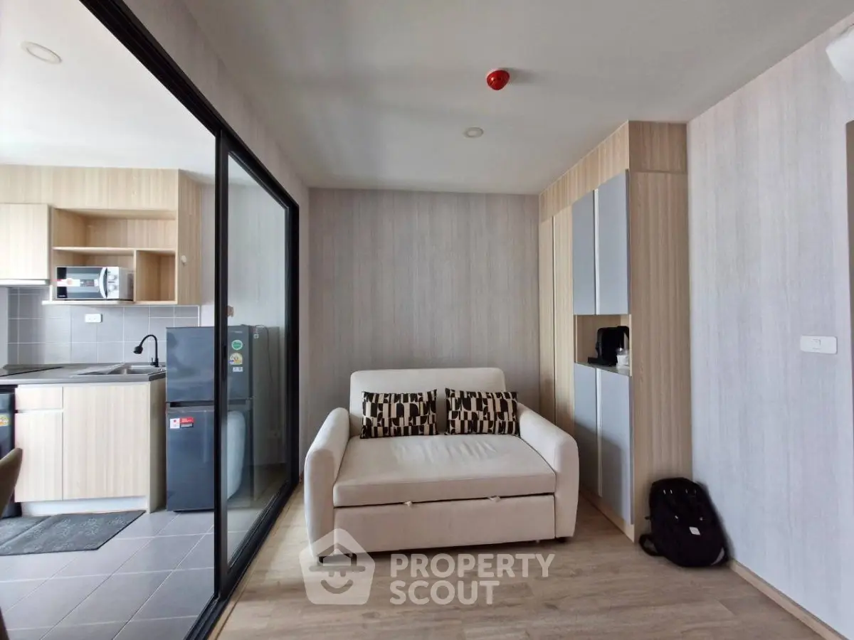 Modern living room with cozy sofa and stylish kitchen in open layout apartment.
