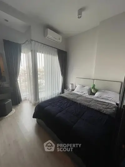 Modern bedroom with large window and stylish decor in a high-rise apartment.