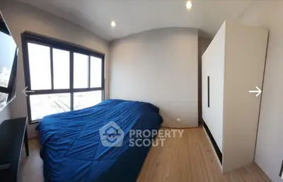 Modern bedroom with large window and blue bedding in a stylish apartment.