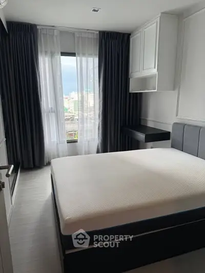 Modern bedroom with large window and stylish furnishings in urban apartment.