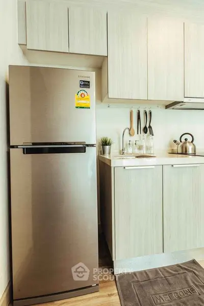 Modern kitchen with stainless steel fridge and sleek cabinetry in compact layout.