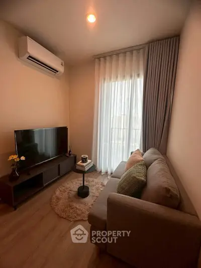 Cozy living room with modern decor, featuring a plush sofa and sleek TV setup.