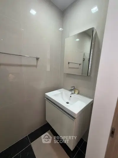 Modern bathroom with sleek sink and mirror in contemporary apartment.