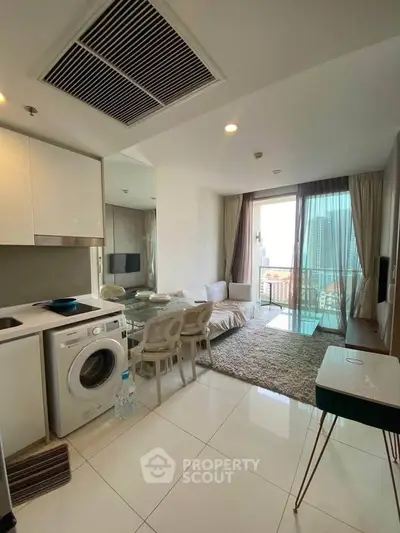 Modern living room with washing machine and balcony view in high-rise apartment.
